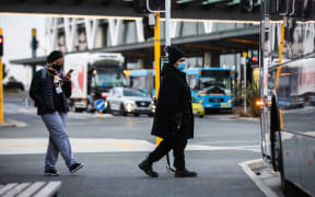 Commuters wearning masks board a bus Manukau