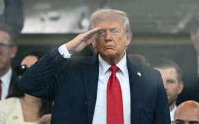 US President Donald Trump stands and salutes during the Army 250th Anniversary Parade from the Ellipse in Washington, DC.