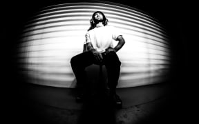 Black and white photo of Tim sitting on a stool.