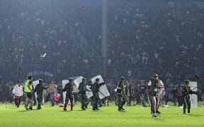 This picture taken on October 1, 2022 shows members of the Indonesian army securing the pitch after a football match between Arema FC and Persebaya Surabaya at Kanjuruhan stadium in Malang, East Java. - At least 127 people died at a football stadium in Indonesia late on October 1 when fans invaded the pitch and police responded with tear gas, triggering a stampede, officials said. (Photo by AFP)