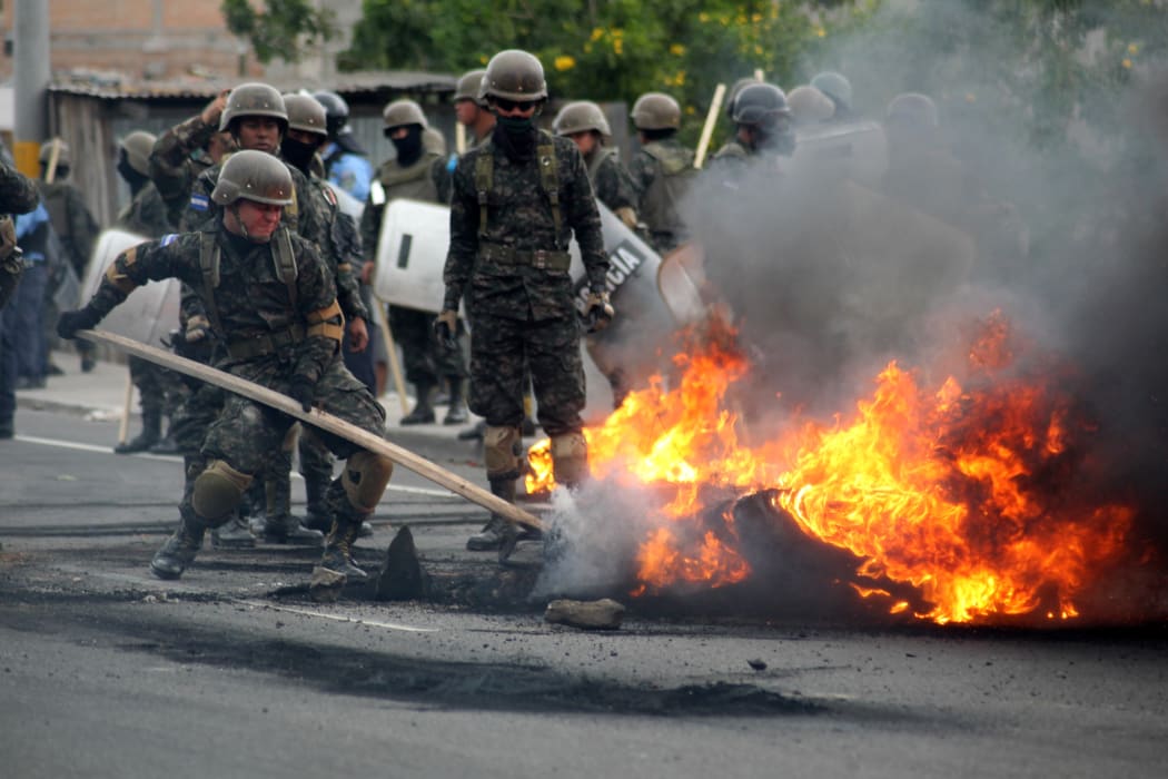 Riot police and soldiers try to remove burnt tires after clashes with supporters of the Honduran Opposition Alliance Against the Dictatorship in Tegucigalpa on Saturday.