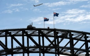 An American Airlines Boeing 777 aircraft flies over the Sydney Harbour Bridge on June 7, 2016. (Photo by William WEST / AFP)