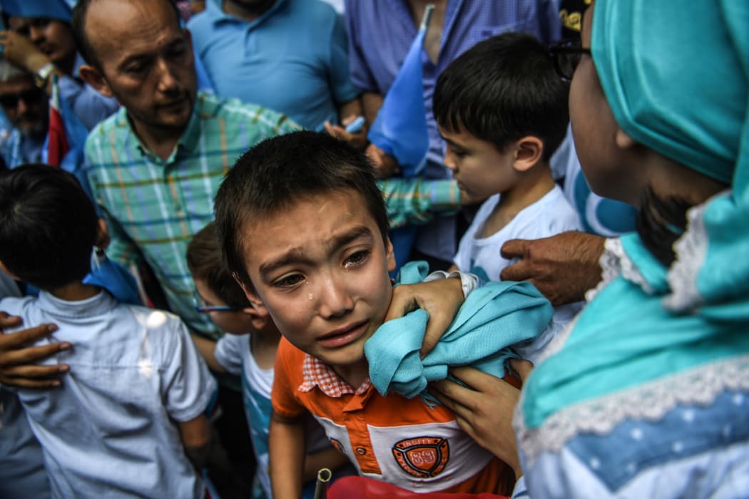 A boy reacts as Turkish plain clothes police officers try push back demonstrators during a protest of supporters of the mostly Muslim Uighur minority and Turkish nationalists to denounce China's treatment of ethnic Uighur Muslims.