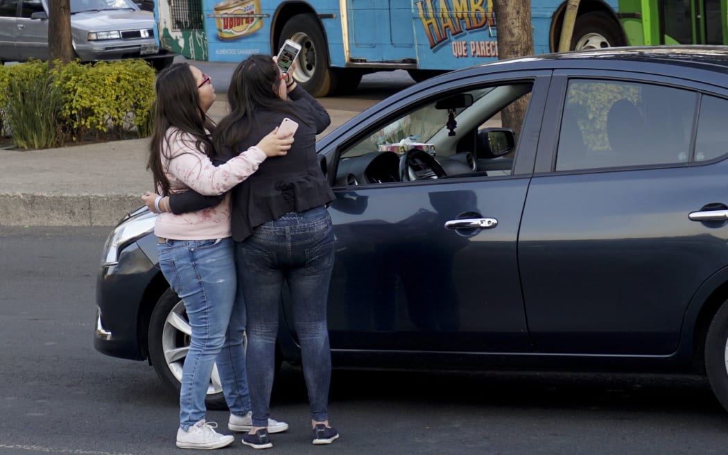 Two women stand by their car during the powerful tremor.