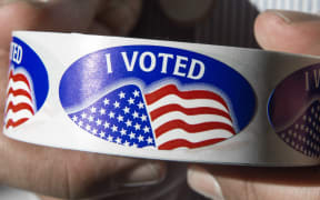 An election official holds a roll of "I voted" stickers at Centreville High School in Centreville, Virginia on 1 March 2016, during the Super Tuesday primary voting.