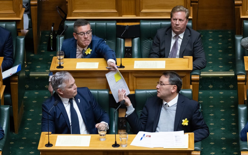 Michael Woodhouse passes back some 'homework' to Shane Reti during Question Time.