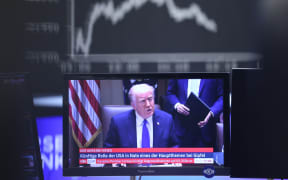 US President Donald Trump is seen on a TV screen below a display showing the German Stock Market Index DAX at the stock exchange in Frankfurt, Germany, on April 3, 2025. (Photo by Daniel ROLAND / AFP)