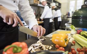 A group of people cooking in a commercial kitchen.