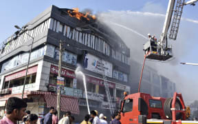 Firefighters work to douse flames on a building in Surat, in the western Indian state of Gujarat, Friday, May 24, 2019.