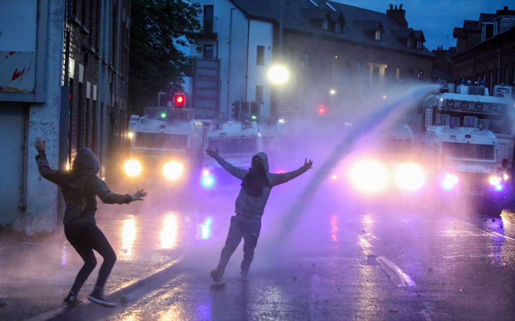 Riot Police use a water cannon in an attempt to disperse protestors gathered for a thrid night of anti-immigration demonstrations, in Ballymena, Northern Ireland, on June 11, 2025. Police were braced late Wednesday for a third night of violence in a riot-hit town in Northern Ireland as hundreds gathered on the streets armed with molotov cocktails and unrest spread to other areas. The riots erupted after the arrest of two teenagers accused of attempting to rape a young girl. The pair appeared in court on Monday where they asked for a Romanian interpreter. (Photo by PAUL FAITH / AFP)