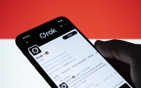 Grok's profile on social network X appears on a smartphone screen with the Indonesian flag in the background. Grok, Elon Musk's AI integrated into X, faces a regulatory crisis after enabling the generation of nude images of public figures and minors from a single imported photo in Creteil, France, on January 16, 2026. (Photo Illustration by Samuel Boivin/NurPhoto) (Photo by Samuel Boivin / NurPhoto via AFP)