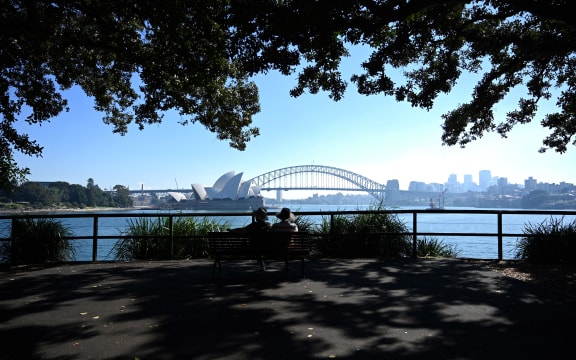 A couple enjoy the view of Sydney Harbour from Mrs Macquarie's Chair on May 3, 2021, as Australia's largest city is enveloped in a thick bank of hazardous bushfire smoke forcing authorities to scale back controlled forest burning nearby.