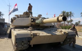 Iraqi security forces stand next to a tank as they clear al-Sajarya district on the eastern outskirts of Ramadi, the capital of Anbar province.