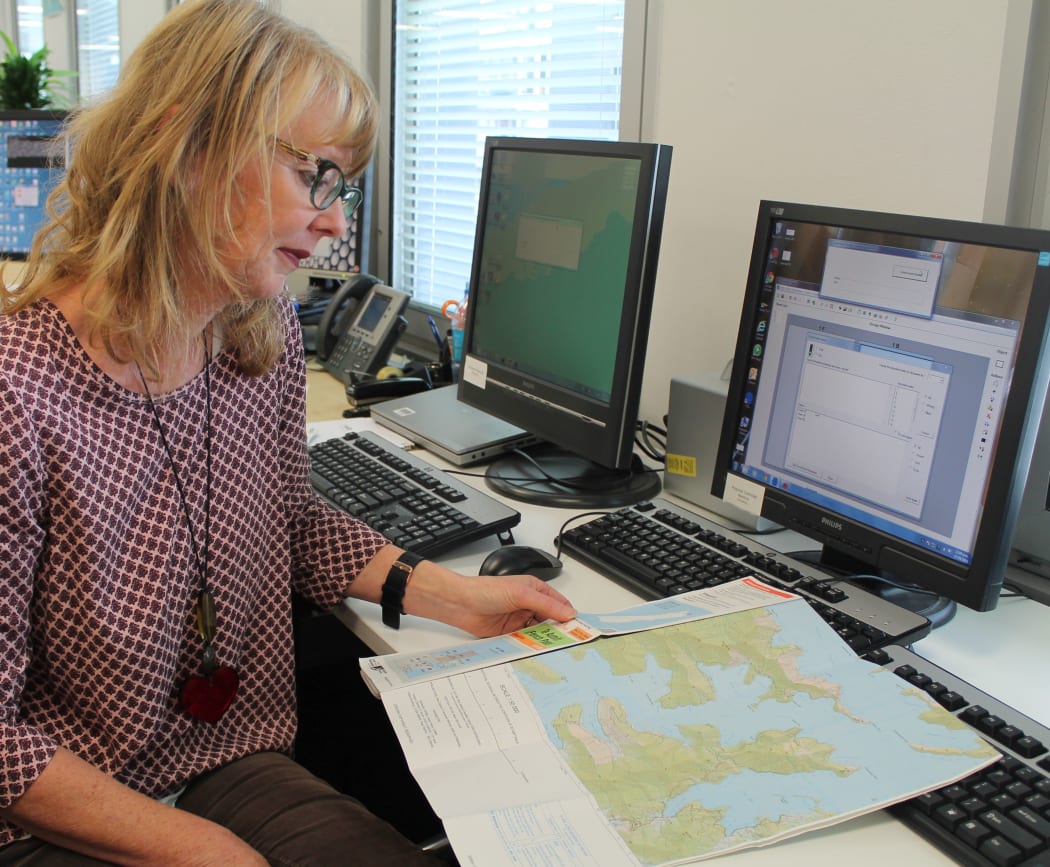 Fran looking at a topo map, seated next to a computer