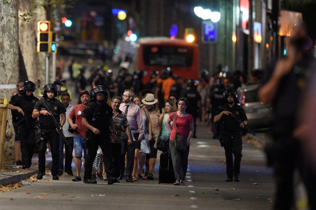 Policemen accompany clients of a store outside a cordoned off off area after a van ploughed into the crowd, killing 13 persons and injuring over 80 on the Rambla in Barcelona on August 17, 2017.