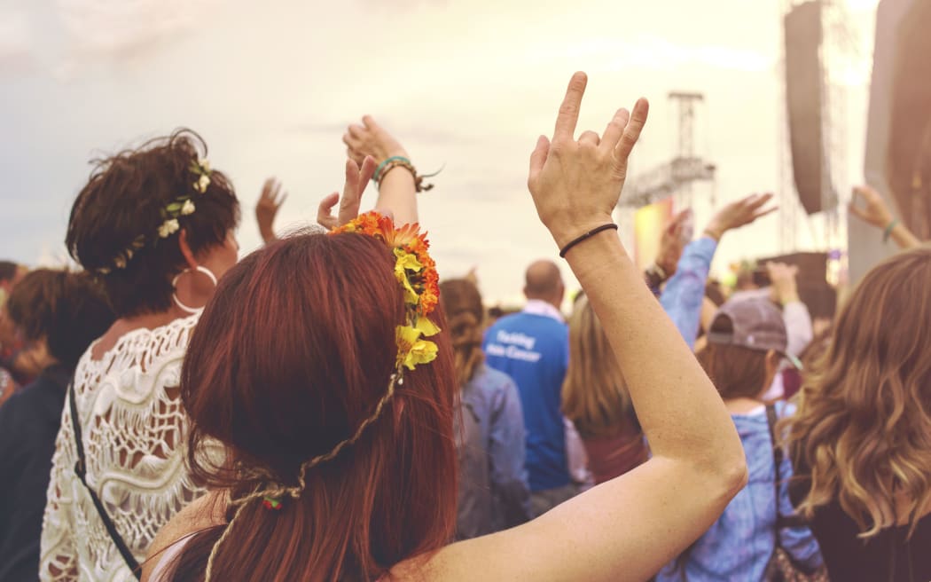 Crowd at an outdoor music festival with outstretched arms