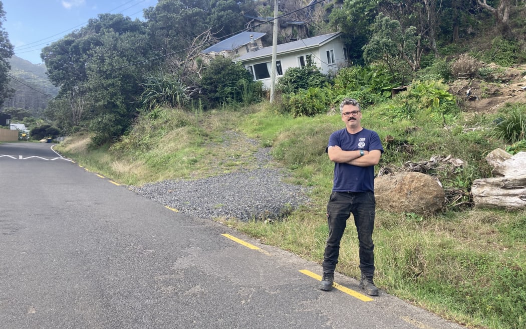 Toby stands at a slip on Karekare Road, one year on from the cyclone.