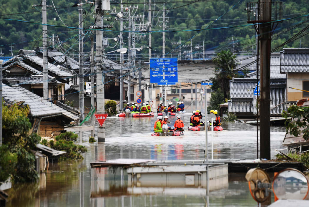 Fire fighters conduct researches at the residential area covered with water in Kurashiki, Okayama Prefecture on July 8, 2018.