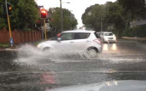 A car drives through surface flooding on Gillies Ave, Auckland.