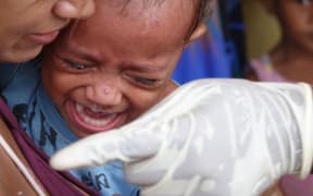 A child is immunised for measles in Vanuatu following Cyclone Pam.