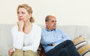 Angry mature married couple having quarrel at living room