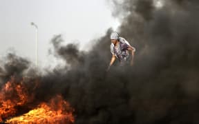 A Palestinian demonstrator walks in the billowing smoke during clashes with Israeli forces along the border of the Gaza strip.
