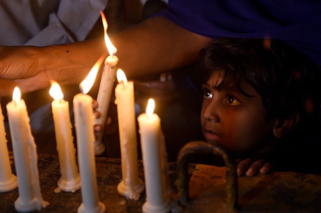 A Pakistani Christian child looks on as adults light candles to pay tribute to Sri Lankan blasts victims in Karachi on April 21, 2019.