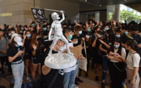 A man carries a miniature statue as protesters and supporters gather outside the entrance to the West Kowloon Court in Hong Kong on October 2, 2019, where some 96 protesters arrested and charged with rioting during clashes with police on September 29 were to make an appearance in court.