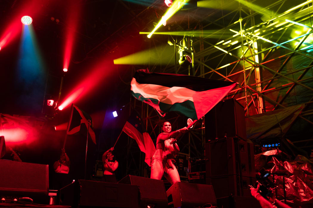 Te KuraHuia waves the Palestinian flag on stage with Lady Shaka at Splore