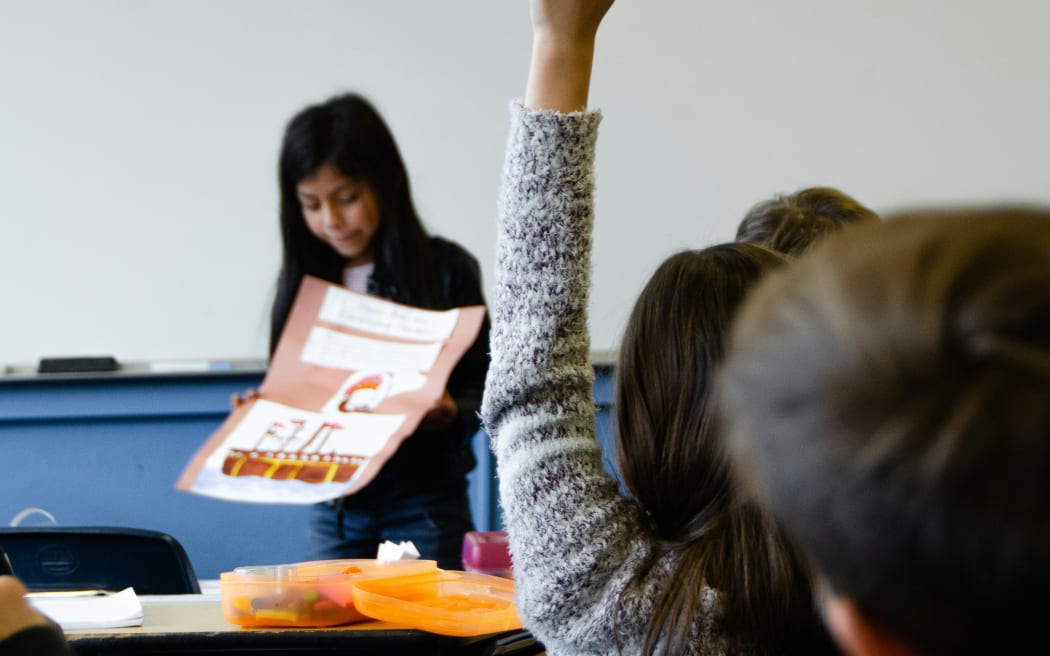 A child raises their hand in class at school.