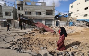 A woman walks over a destroyed road in the aftermath of an Israeli strike in Khan Yunis in the southern Gaza Strip on 14 May, 2025.