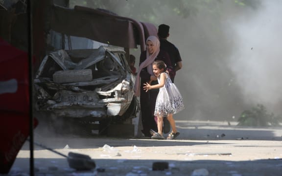 A Palestinian mother and her daughter rush for cover during an Israeli strike in the Al-Bureij camp in the central Gaza Strip.