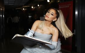 Ariana Grande at the Grammy Awards. She is wearing a grey dress.