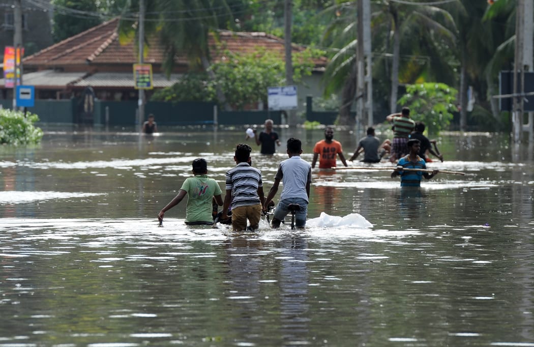 Sri Lankan residents look on from a shop surrounded by floodwaters in Nagoda in Kalutara district.