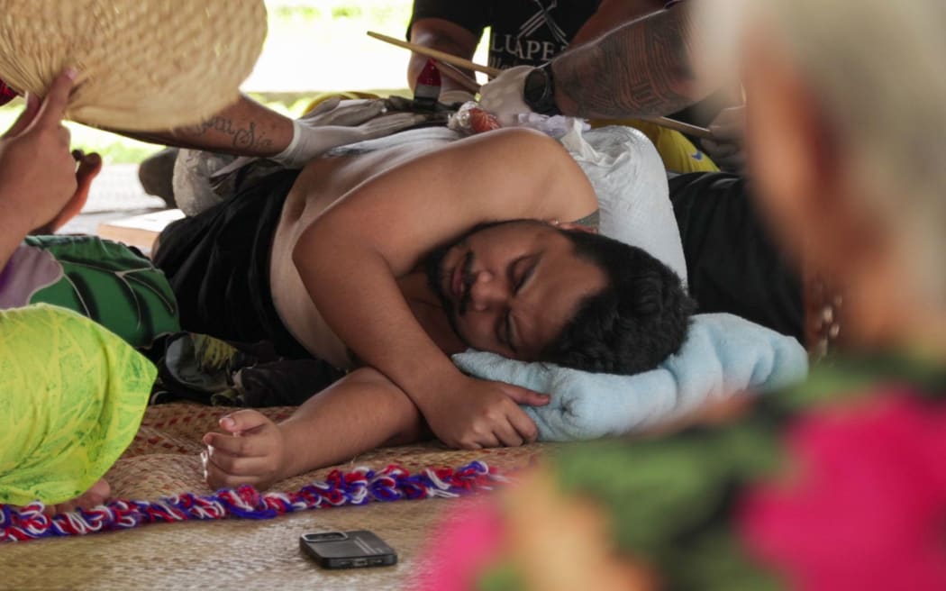 Anric's grandmother looks on during a tatau session