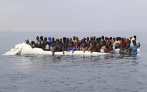 A file photo shows people waiting to be rescued from a sinking dinghy off the Libyan coastal town of Zawiyah, east of the capital, on 20 March, 2017, as they attempted to cross from the Mediterranean to Europe.