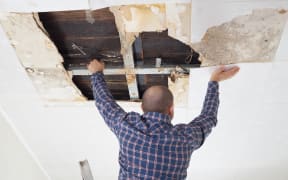 Man repairing collapsed ceiling. Water damaged ceiling from leak.