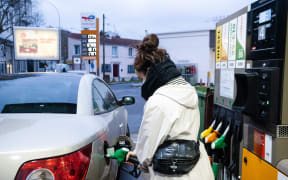 A woman fills a car with petrol in Paris, February 2022.