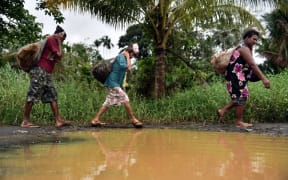Women carry wood in the town of Kerema, Papua New Guinea