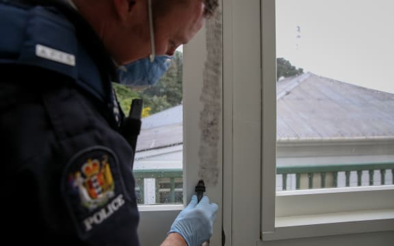 Constable Richard Matthews dusts for fingerprints on a door where a suspected burglary took place.