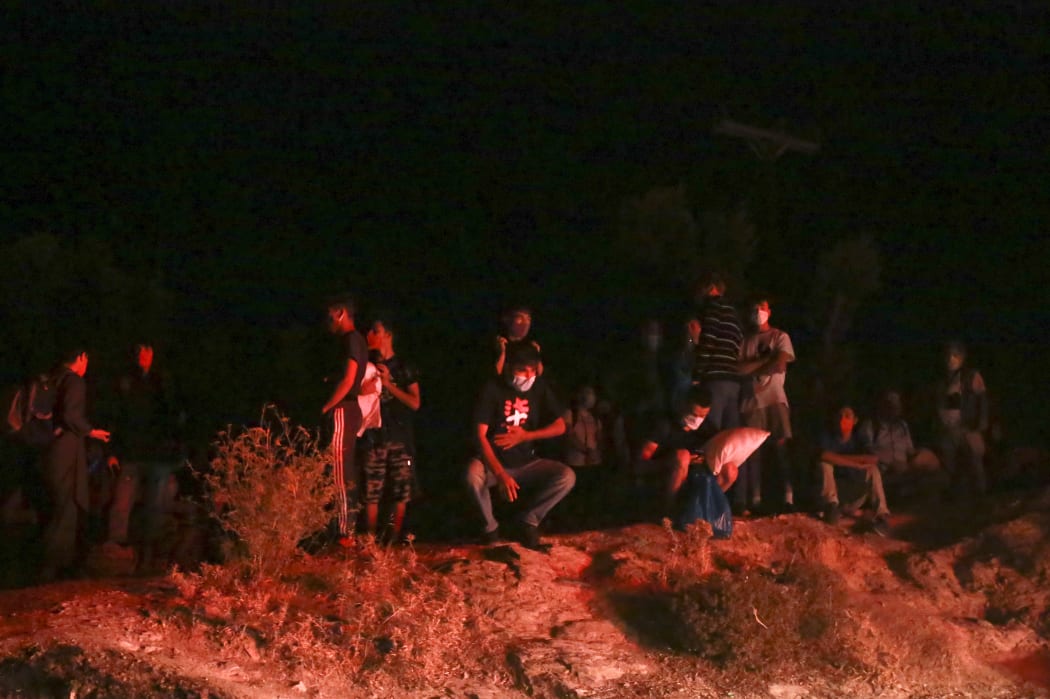 Migrants wearing masks gather outside the Moria camp on the island of Lesbos during a major fire there on September 9, 2020.