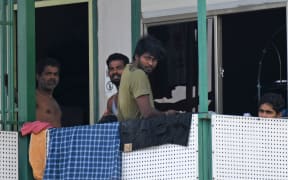 Men look out from a dormitory used by foreign workers at Cochrane Lodge 2, which has been made an isolation area to prevent the spread of the COVID-19 coronavirus, in Singapore on April 15, 2020.