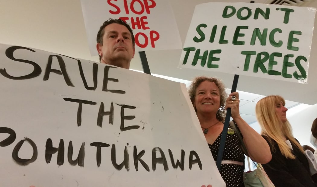 Tim O'Shea and Christine Rose come with placards to the board meeting.