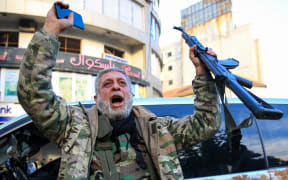 A Syrian rebel fighter who returned to the central city of Homs on December 8, 2024, after being in exile for 12 years celebrates after rebel forces entered Syria's third city overnight.
