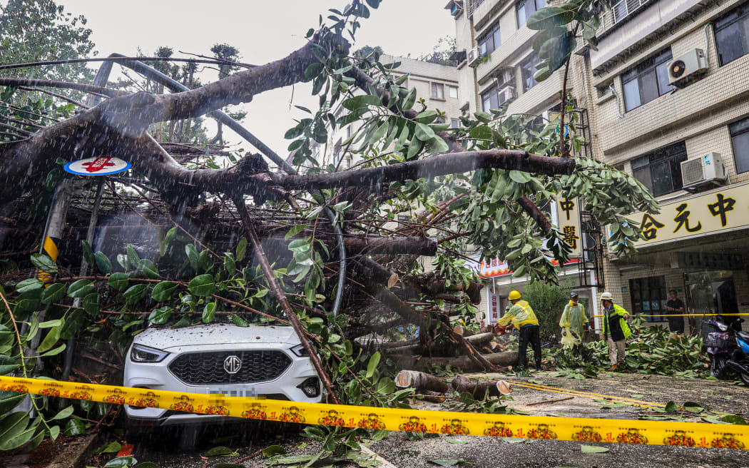 This picture taken and released by Taiwan’s Central News Agency (CNA) on October 31, 2024 shows a car under an uprooted tree at New Taipei City, as Super Typhoon Kong-rey neared the coast in Taitung. - Super Typhoon Kong-rey made landfall in Taiwan on October 31, the state weather forecaster said, as one of the most powerful storms to hit the island in years unleashed fierce winds and torrential rain. (Photo by CNA / AFP) / China OUT - Taiwan OUT - Macau OUT / CHINA OUT - TAIWAN OUT - MACAU OUT / HONG KONG OUT RESTRICTED TO EDITORIAL USE