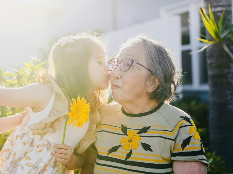 A young girl kisses an elderly woman on the cheek
