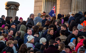 People line up to pay their respects as an elderly man salutes crowd during the Anzac dawn service in Melbourne.