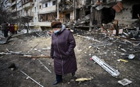 A woman walks in front of a damaged residential building at Koshytsa Street, a suburb of the Ukrainian capital Kyiv, where a military shell allegedly hit, on February 25, 2022.