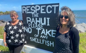 Pākehā Lynley Johnson (left) hand-painted a sign for the Rāhui at Bayly Road and hands out brochures with Katerina Finnigan.