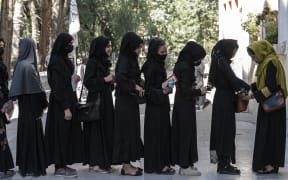 An Afghan female guard frisks students before they sit for entrance exams at the Kabul University in Kabul on 13 October, 2022.